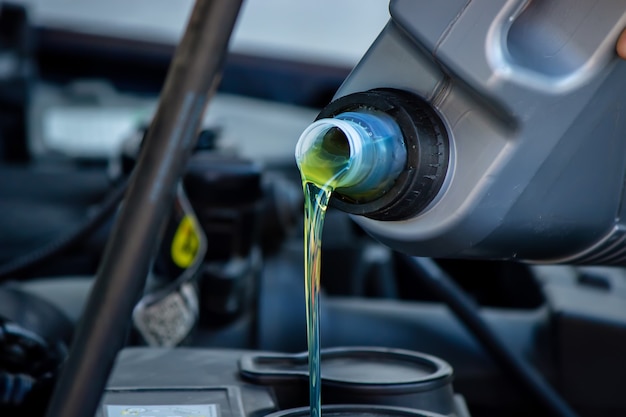 Un meccanico che cambia olio versa olio nel motore di un'auto.