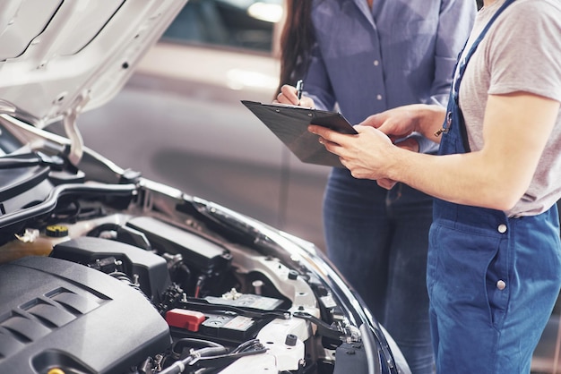 Un meccanico e una cliente guardano il cofano dell'auto e discutono delle riparazioni