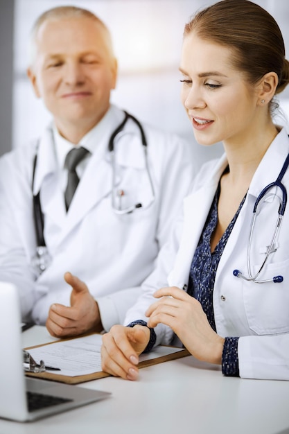 Un medico anziano e la sua collega discutono dell'attuale terapia della malattia mentre si siedono sul posto di lavoro in una clinica soleggiata. Il lavoro di squadra in medicina.