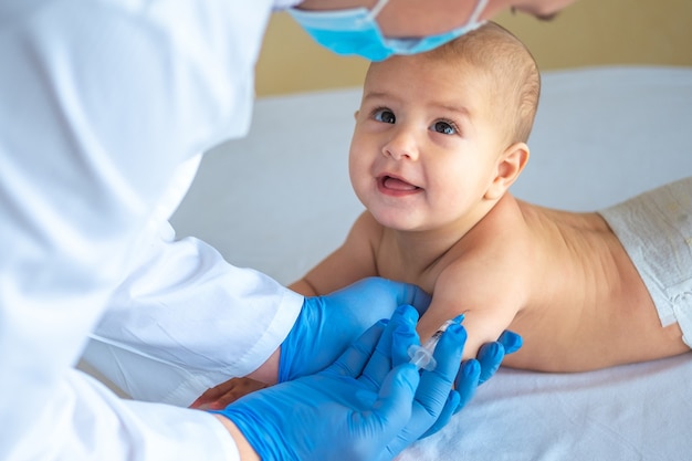 Un medico che dà un vaccino a un bambino in mano. Il bambino felice guarda il medico.