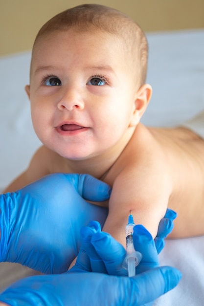 Un medico che dà un vaccino a un bambino in mano.