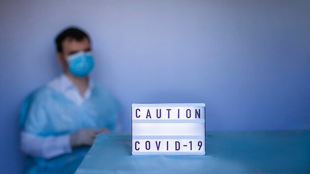 Un medico che indossa una maschera respiratoria e guanti di medicina vicino all'attenzione di Coronavirus