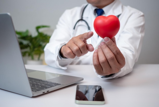 Un medico che mostra un cuore rosso all'ufficio dell'ospedale Concetto di assistenza medica e di servizio del personale medico