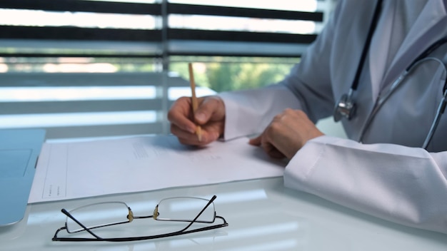 Un medico che scrive su un foglio con una matita.