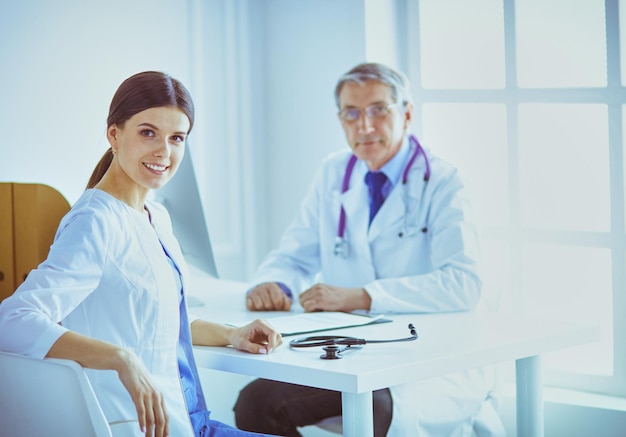 Un medico che sorride alla telecamera con il suo collega di sesso maschile nel retro della stanza di consultazione in ospedale