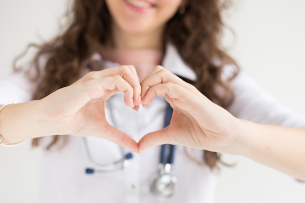 Un medico con il suo stetoscopio mostra il cuore delle mani