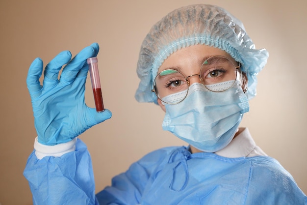 Un medico con maschera protettiva e occhiali tiene in mano una provetta con un esame del sangue positivo per COVID19
