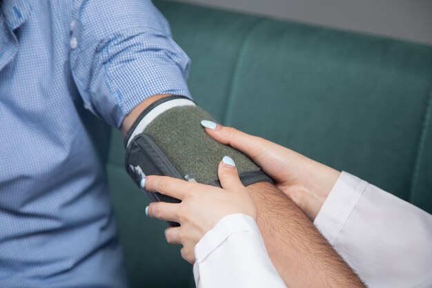 Un medico controlla la pressione sanguigna di un uomo con un dispositivo elettronico sul divano