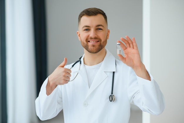 Un medico in guanti blu che tiene una bottiglia con il vaccino. Primo piano. Concetto di medicina e assistenza sanitaria