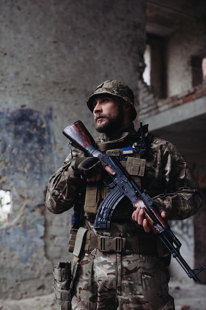 Un militare ucraino pone sullo sfondo di edifici distrutti La guerra tra Ucraina e Russia