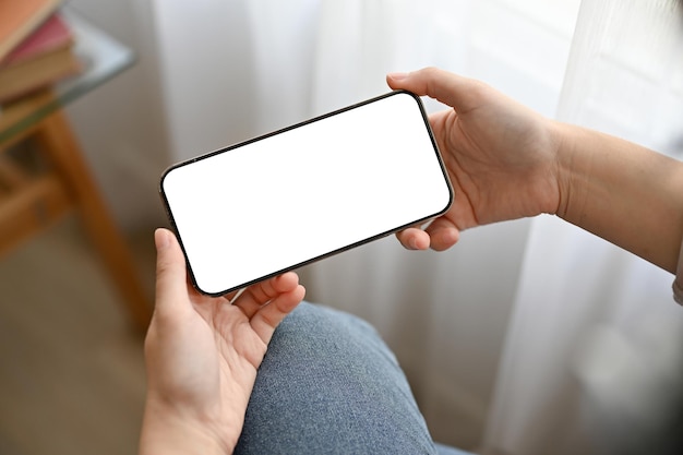 Un mockup di schermo bianco per smartphone è nelle mani di una donna su sfondo sfocato