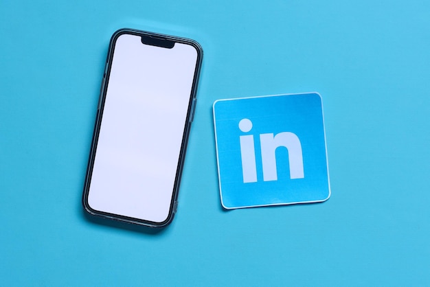 Un mockup di smartphone con schermo vuoto con carta stampata del logo dell'applicazione di social media denominato Linked