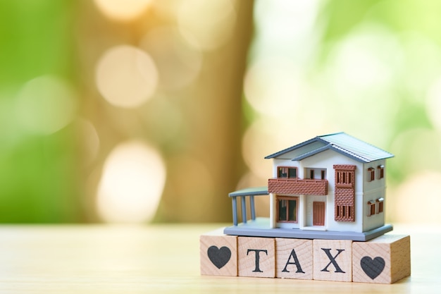 Un modello di casa modello è posto sulla parola legno TAX