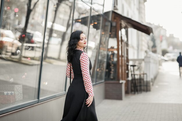 Un modello di moda donna cammina per le strade della città vicino a edifici moderni