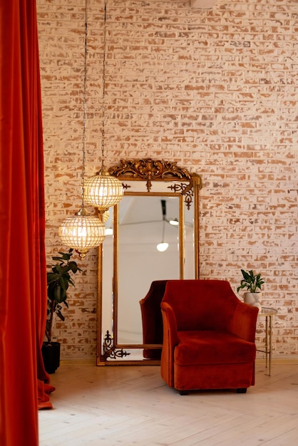Un moderno interno francese con tende in velluto a coste bordeaux una poltrona uno specchio dorato di crescita vintage e lampadari di cristallo contro un muro di mattoni Messa a fuoco selettiva morbida