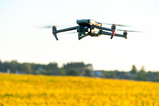 Un moderno quadricottero sorvola un campo di girasoli contro il tramonto L'uso delle moderne tecnologie nel complesso agroindustriale Il drone aiuta l'agricoltore nel settore agroalimentare