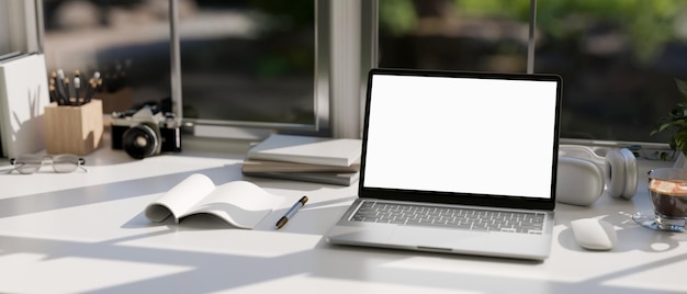 Un moderno tavolo da lavoro per ufficio contro la finestra con mockup di laptop notebook