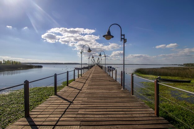 Un molo sul lago con un cielo azzurro e nuvole sullo sfondo.