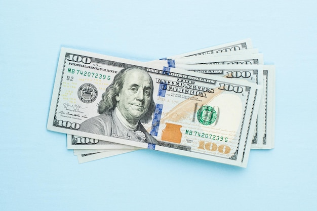 Un mucchio di banconote moderne da 100 dollari su sfondo blu