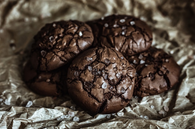 Un mucchio di biscotti al cioccolato con cime incrinate con sale marino su carta artigianale