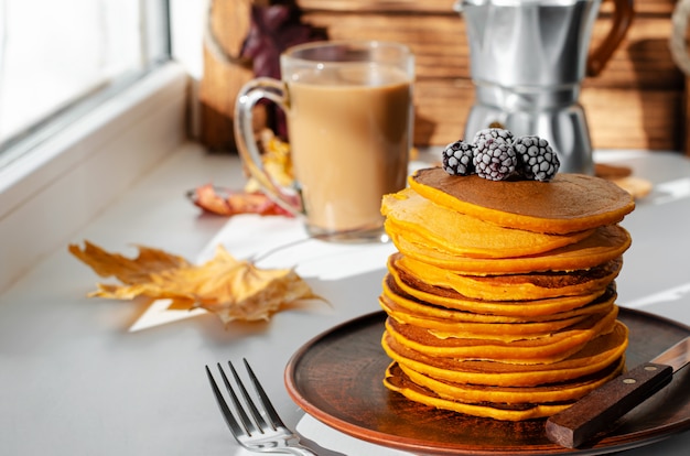 Un mucchio di frittelle di zucca con more. Deliziosa colazione