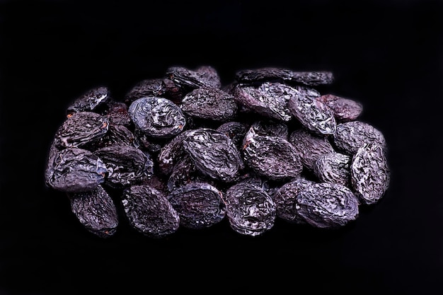 Un mucchio di frutta secca viola scuro si trova su una superficie nera.