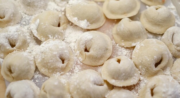 Un mucchio di gnocchi con la farina sul tavolo.