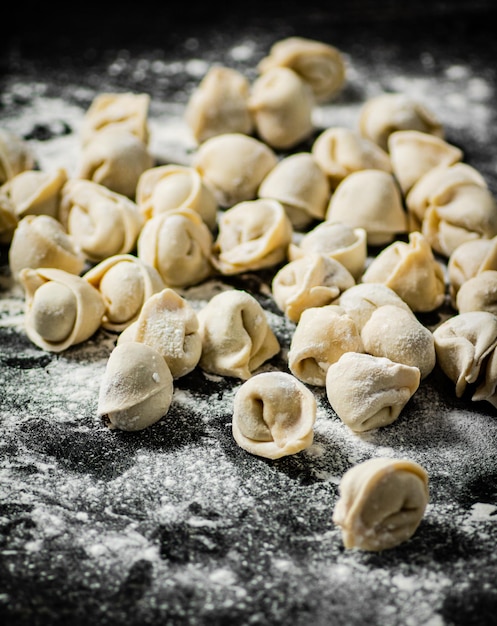 Un mucchio di gnocchi su una superficie infarinata con farina sul lato.