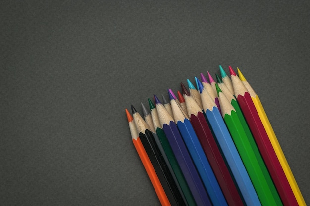 Un mucchio di matite colorate su uno sfondo grigio scuro