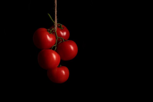 Un mucchio di pomodori rossi appesi a una corda in cucina