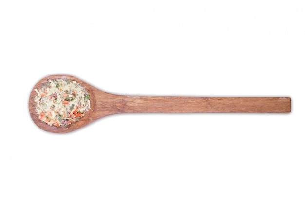 Un mucchio di un mix di spezie giallo sul cucchiaio di legno isolato su bianco Le spezie sono costituite da verdure disidratate essiccate carota cipolla paprika aglio prezzemolo prezzemolo