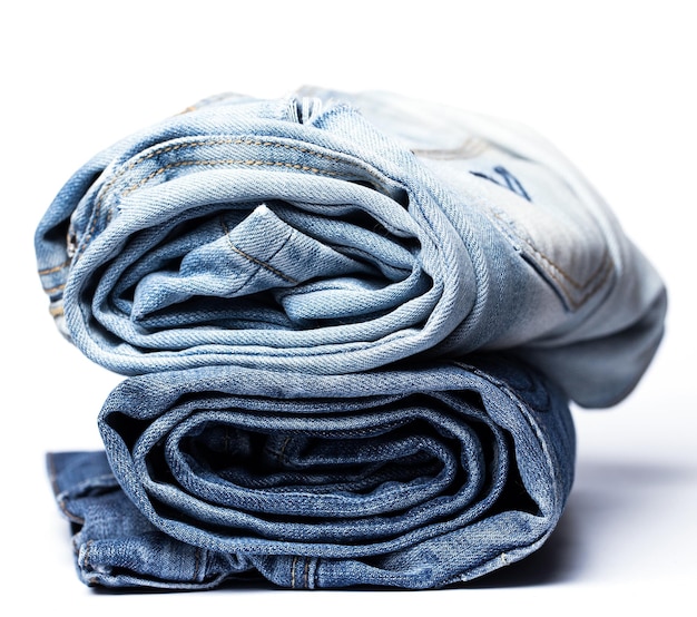 Un mucchio di varie paia di jeans su uno sfondo bianco