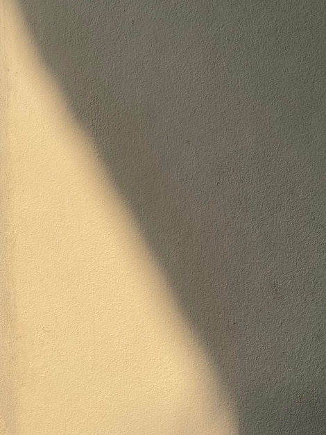 Un muro beige con un'ombra di luce sopra.