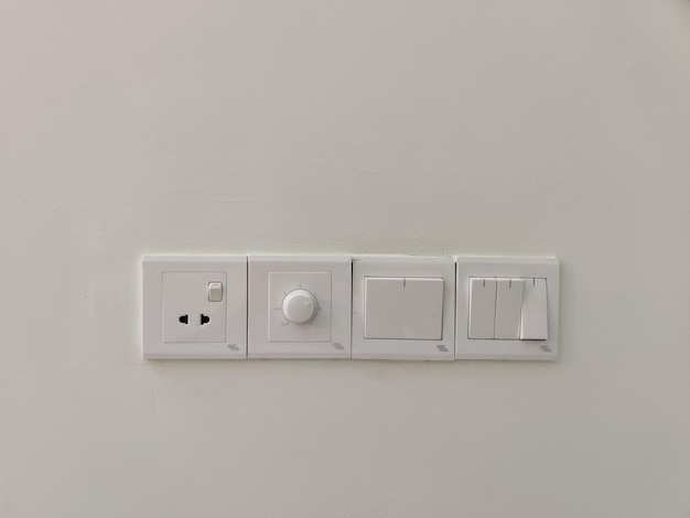 Un muro bianco con un interruttore bianco e un pulsante bianco.