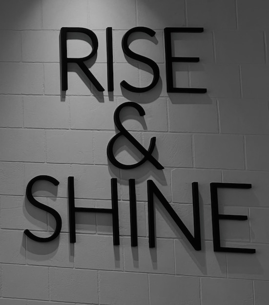 un muro di mattoni con le parole "Rise and shine"