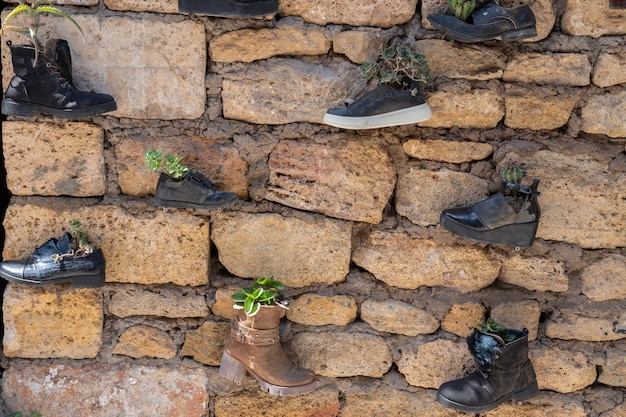 Un muro di mattoni con scarpe da cui crescono fiori decorazioni murali