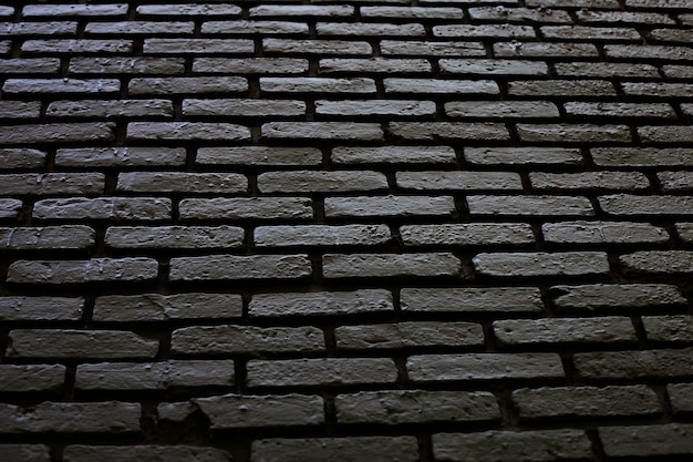 Un muro di mattoni con uno sfondo scuro e un muro di mattoni scuri con una luce che risplende su di esso.