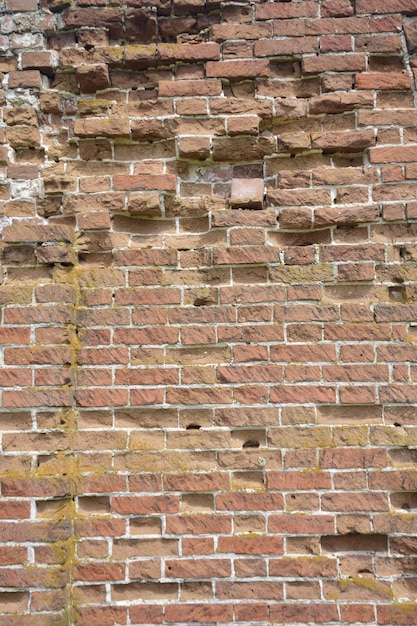 Un muro di vecchi mattoni incrinati con una superficie alterata e sbiadita Muratura restaurata di una vecchia casa