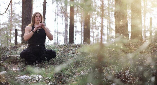 Un musicista con uno strumento in natura. L'uomo sta suonando un flauto in una pineta. La musica dei druidi nella foresta primaverile.