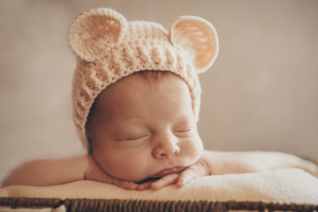 un neonato con un cappello lavorato a maglia con orecchie. Imitazione di un bambino nel grembo materno. Ritratto di un neonato. Il concetto di salute, genitorialità, festa dei bambini, medicina, fecondazione in vitro