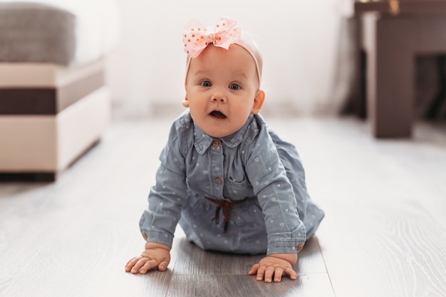 Un neonato di una ragazza carina striscia sul pavimento della stanza. Un bambino impara a gattonare