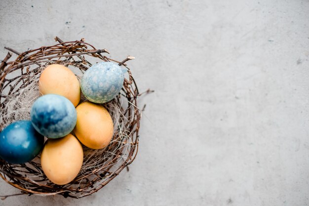 un nido e diverse uova con bastoncini di salice. Priorità bassa di pietra grigia astratta, concetto felice di pasqua