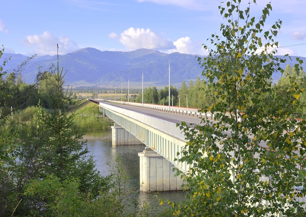 Un nuovo ponte sul fiume Katun nei monti Altai sotto un cielo blu Siberia Russia