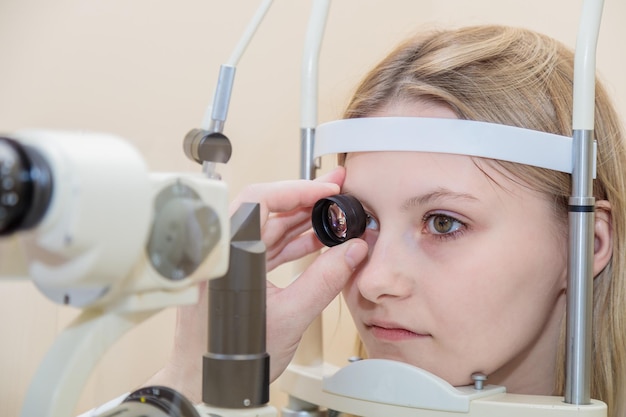 Un oftalmologo controlla la vista di una ragazzina usando un moderno apparecchio con un raggio luminoso