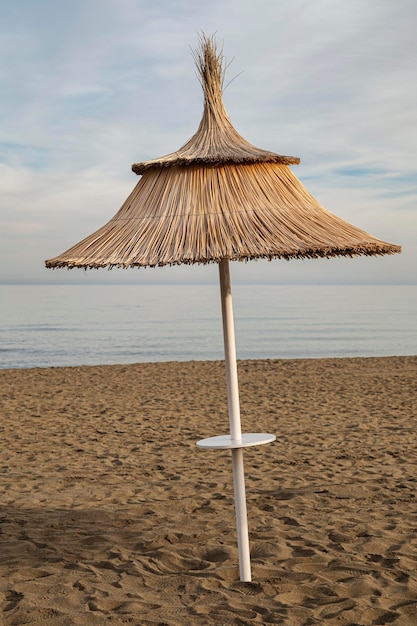 Un ombrello di paglia in primo piano su una spiaggia al tramonto in un ambiente calmo e sereno senza persone