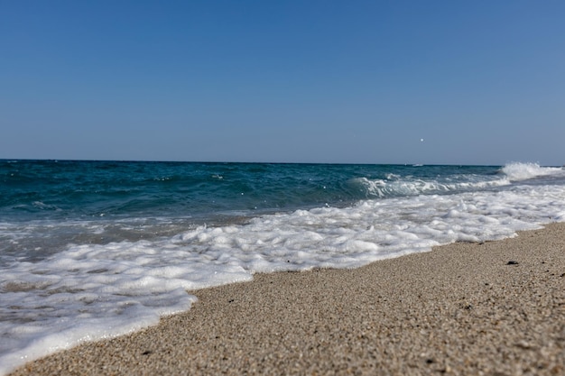 Un onde bianche nel mare blu sulla spiaggia