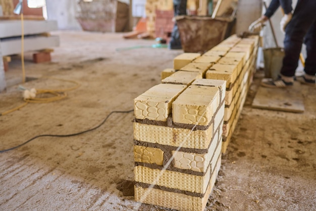 Un operaio edile sta mettendo con competenza i mattoni sul cantiere con precisione e abilità