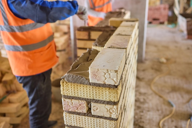 Un operaio edile sta mettendo con competenza i mattoni sul cantiere con precisione e abilità