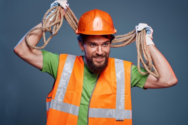 Un operaio edile uomo barbuto in una corda di sicurezza casco arancione nelle sue mani