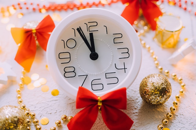 Un orologio nel layout di un nuovo anno su uno sfondo bianco. Regali di Capodanno. Un articolo sul Capodanno e il Natale.